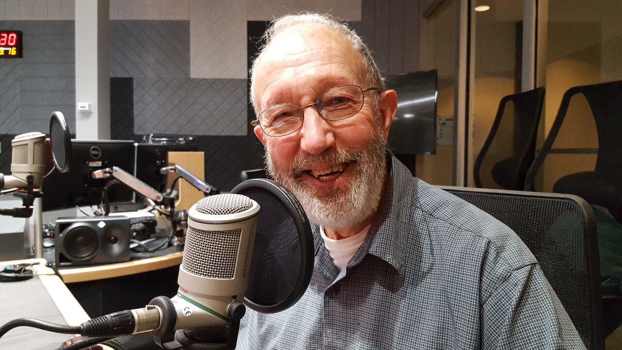Roger Nash at a radio studio microphone, smiling